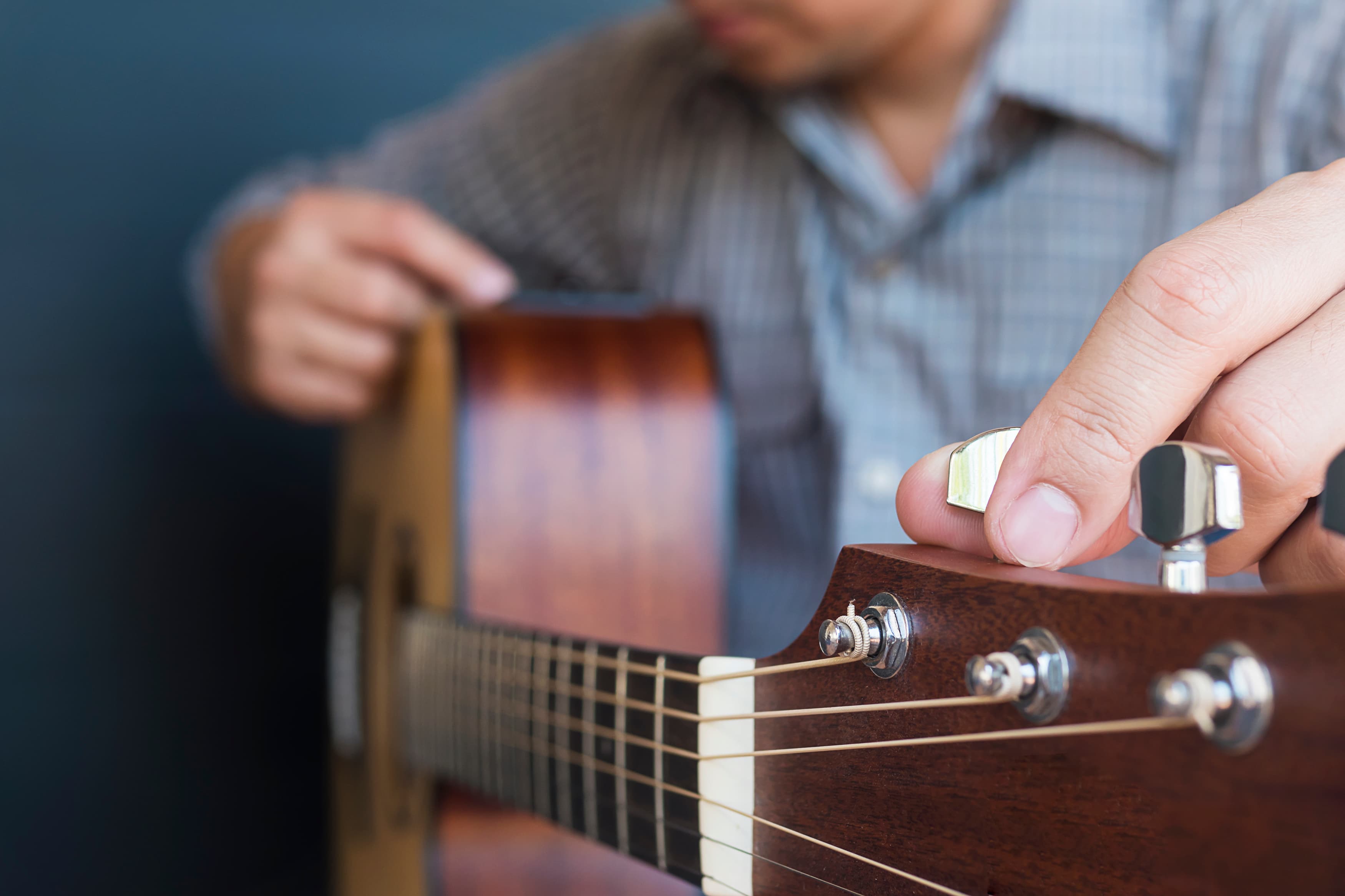 Fotografia fotorealista de um homem com a mão na tarracha de um violão afinando a corda do instrumento.